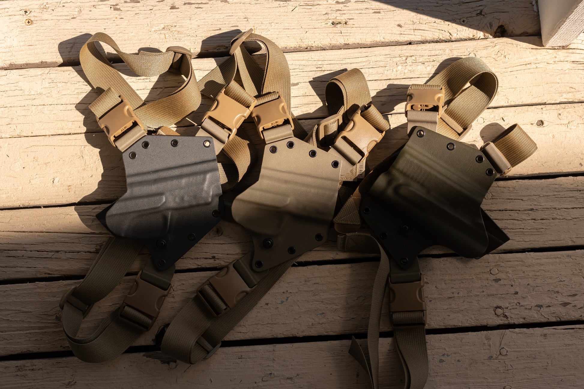 Three Arctos Arms Chest holsters, one of each color. Grey (left), FDE tan (middle), OD green (right).